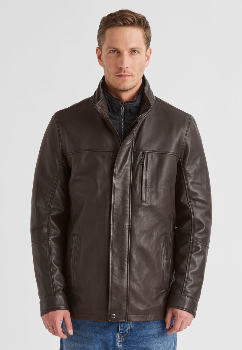 Braune Lederjacke mit Stehkragen, einer Reißverschlusstasche vorne und seitlichen Taschen. Glatte Textur und taillierte Passform, kombiniert mit lässigen Jeans.