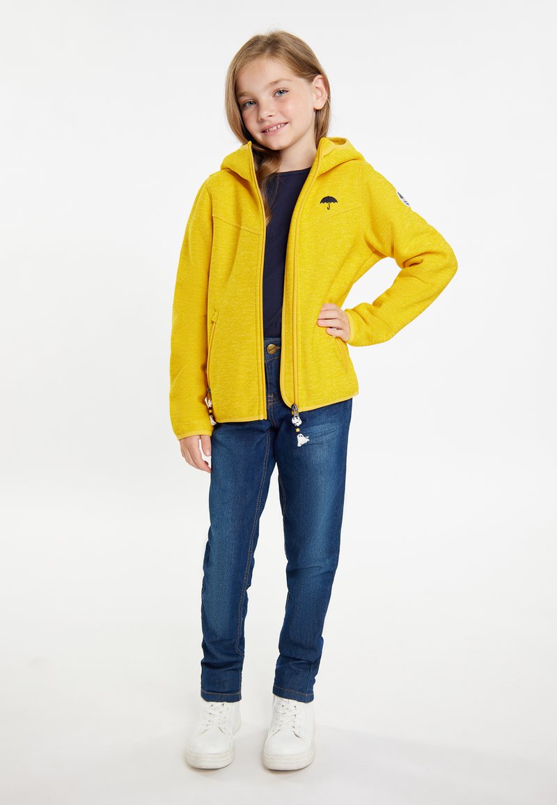 Gul zip-up hoodie med en mjuk textur, med en framficka och logotyp. Matchad med blå denimjeans och vita sneakers.