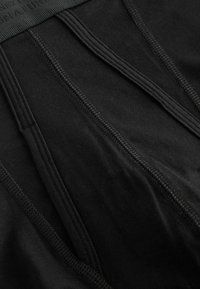 Schwarze Baumwollunterhose aus weichem Stoff, mit elastischem Bund und Steppdetails sowie einer glatten Textur. Minimalistisches Design, das auf Komfort fokussiert ist.