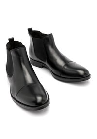 Czarne skórzane botki za kostkę z gładkim wykończeniem, elastycznymi panelami po bokach i okrągłymi palcami z designem na czubkach. Płaska, syntetyczna podeszwa.