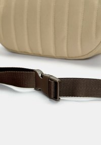 Borsa in tessuto beige con righe verticali, dotata di una tracolla regolabile marrone e una fibbia in plastica. Texture liscia e design robusto per garantire durata nel tempo.