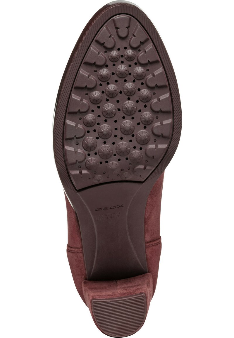 Zool van een bordeauxrode suede dames schoen met cirkelvormige en gebogen tredpatronen en een kleine blokhak.