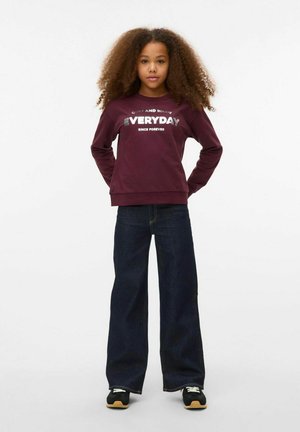 Bordaux sweatshirt met "EVERYDAY" in zilveren tekst, gecombineerd met een donkerdenim wijde broek en zwarte sneakers met lichte accenten.