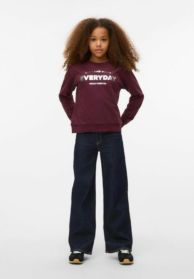 Sweat-shirt bordeaux avec "EVERYDAY" en texte argenté, associé à un pantalon en denim large bleu foncé et des baskets noires avec des accents clairs.