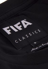 Zwarte stoffen label met witte tekst "FIFA CLASSICS" en maat "S." Label bevat onderaan de vermelding "Gemaakt in Europa."