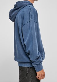 Felpa in cotone blu con una vestibilità comoda, cappuccio con cordino e polsini e orlo a costine. Presenta una texture morbida e dettagli minimi.