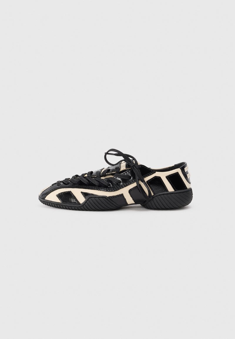 Black and cream athletic shoe with a textured upper, featuring cut-out designs, laces, and a ridged sole for traction.