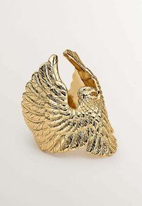 Anillo en forma de águila dorada con plumas texturizadas y diseño de espalda abierta, que resalta los intrincados detalles y un acabado metálico.