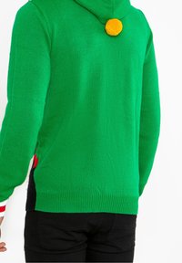 Pull en tricot vert avec capuche, orné d'un pompon jaune, d'accents latéraux rouges et noirs, ainsi que de poignets et d'un ourlet côtelés.