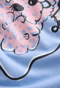 Primo piano di tessuto con forme di stampa leopardata rosa e blu contornate di nero su sfondo azzurro chiaro.