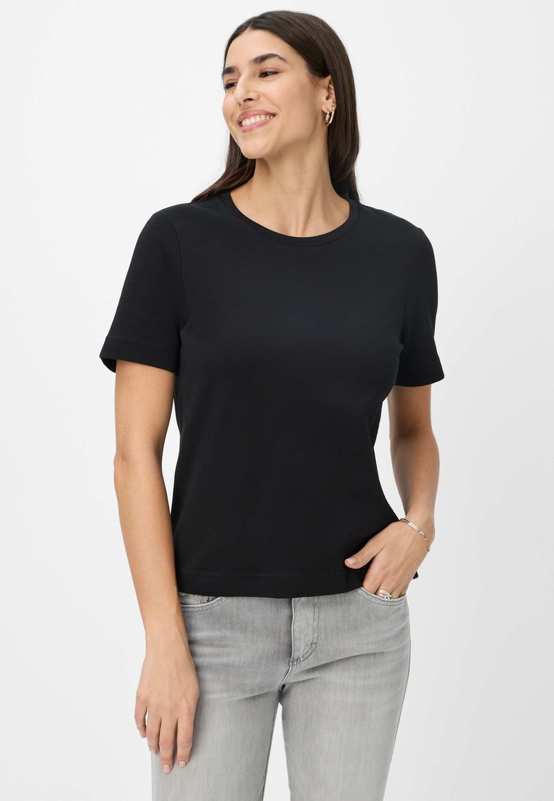 Schwarzes Kurzarm-T-Shirt mit Rundhalsausschnitt, aus glattem Stoff gefertigt. Getragen mit hellgrauen Jeans, die einen bequemen Sitz bieten.