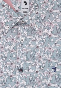 Lichtblauwe shirt met wit en roze bloemmotief, witte knopen en label "J&JOY Designed in Belgium" bij de kraag.