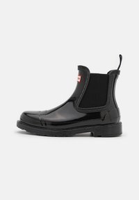 Zwarte rubberen Chelsea boots met elastische zijden, een gladde glanzende afwerking en een trekkoord aan de achterkant. Inclusief een getextureerde zool voor grip.
