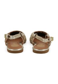 Sandali in oro intrecciato con suola piatta, cinturino alla caviglia regolabile e una soletta marrone liscia. Presentano dettagli metallici sui bordi.