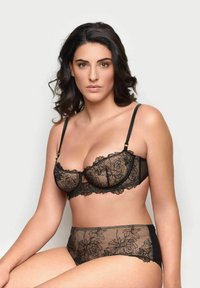 Černá krajková podprsenka a odpovídající vysoké kalhotky s květinovými vzory. Měkký materiál; průhledné části s jemným zdobením. Delikátní akcenty.