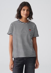 Black and white striped t-shirt made of cotton, featuring short sleeves, a round neckline, and a small red heart logo on the chest.