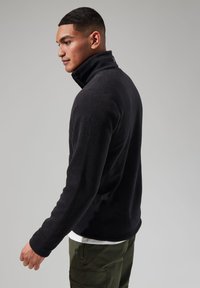 Black fleece pullover with a high collar and long sleeves, featuring a smooth texture and subtle logo detail on the back neckline.