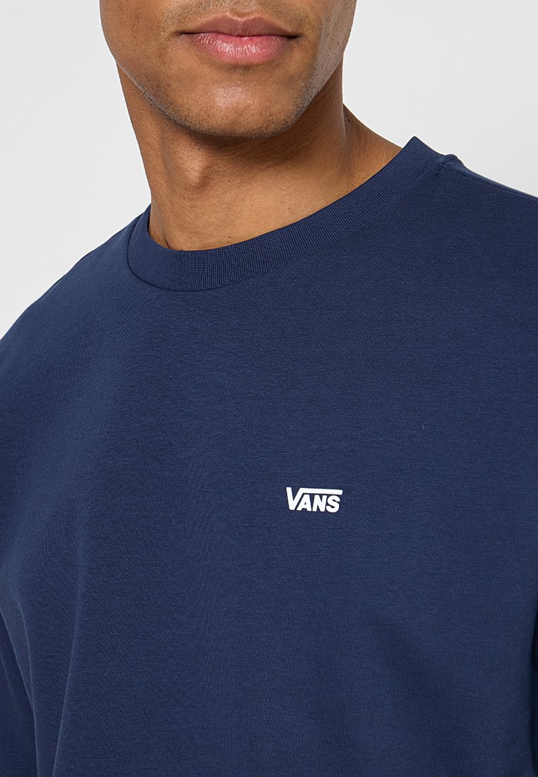 Marineblauwe katoenen sweatshirt met een ronde hals en een klein wit "VANS" logo op de linkerborst. Gladde textuur.
