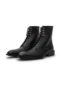 Schwarze Leder-Ankle-Boots mit runder Zehenform, Schnürung vorne und metallischen Ösen. Der flache Absatz und die glatte Textur runden das Design ab.