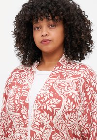 Lehký kimono s korálovým vzorem a květinovým designem v krémové barvě. Má otevřený přední díl a volné rukávy pro snadné nošení.