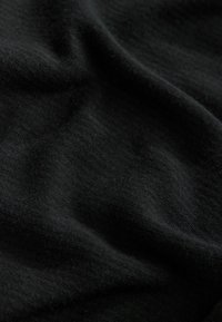 Black fabric with a soft texture, featuring subtle folds and a smooth, slightly textured surface. No patterns or hardware visible.