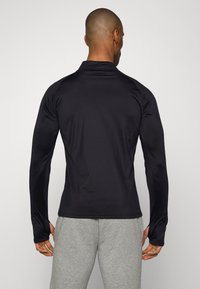 Schwarzes Langarmshirt mit taillierter Passform, aus glattem, dehnbarem Stoff gefertigt, mit hohem Kragen und nahtlosen Schultern.