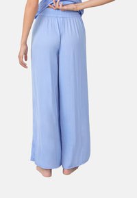 Lichtblauwe wijde broek met een elastische tailleband. De stof heeft een gladde textuur, ontworpen voor comfort met een ontspannen pasvorm.