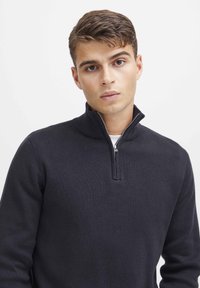 Marineblaues Strickpullover aus strukturiertem Stoff, mit einem halben Reißverschluss am Kragen und gerippten Bündchen an den langen Ärmeln, in schmaler Passform.