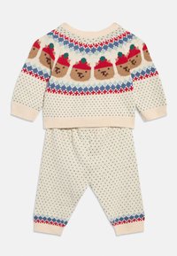 Σετ πλεκτού εκρού πουλόβερ και παντελονιού με πολύχρωμο μοτίβο αρκούδας και βελανιδιού, διακοσμημένο με κόκκινες, μπλε και πράσινες λεπτομέρειες, με υφή που έχει κουκκίδες.