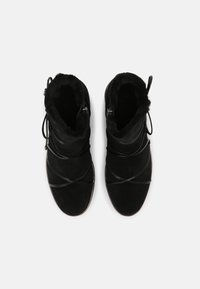 Bottines en daim noir avec doublure en fausse fourrure, dotées de lacets croisés et d'un design à bout rond. Talon plat pour un confort optimal.