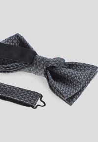 Granatowy muszka z złożoną, jasną tkaniną, posiadająca gładki, czarny, regulowany pasek oraz teksturowane wykończenie w kokardzie.