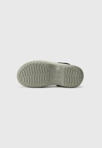 Black sandal with a textured lightweight sole, featuring a patterned tread and the logo. Smooth straps made from flexible material.