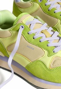 Green and beige sneakers with suede and synthetic material, featuring lilac laces, textured accents, and "HOFF" branding in light blue.