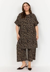Brun leopardmönstrad tunika och cropped byxor set, gjort av lättviktsmaterial. Har korta ärmar och en avslappnad passform. Bruna slingback-skor.