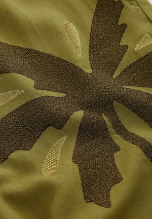Textil mit einem olivgrünen Hintergrund und einem dunkelbraunen Blattdesign. Das Blatt hat eine strukturierte Oberfläche und goldene Akzente.