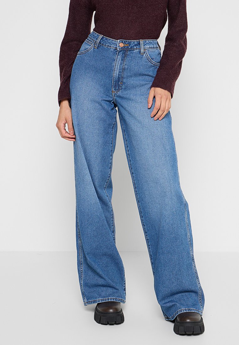 Jeans z wysokim stanem w niebieskim kolorze, o szerokim kroju nogawki, z zapięciem na guzik z przodu oraz kieszeniami bocznymi, o gładkiej fakturze i klasycznym przeszyciu.