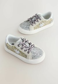 Zapatillas brillantes con destellos plateados y dorados, cordones con estampado de leopardo, suela de goma blanca y acento de estrella en el lado.