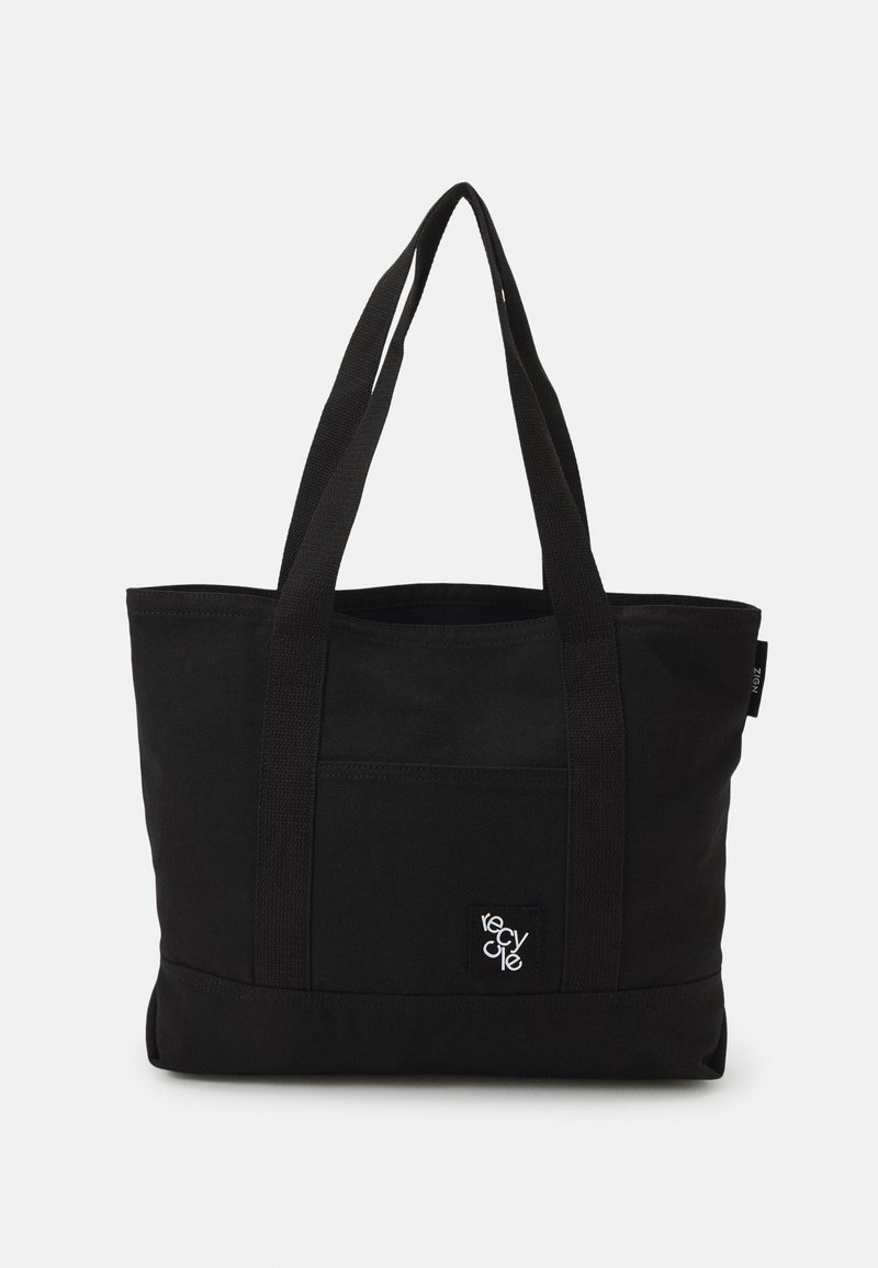 Black canvas tote bag featuring two sturdy handles, a front pocket, and a small logo patch. Simple rectangular design and matte texture.