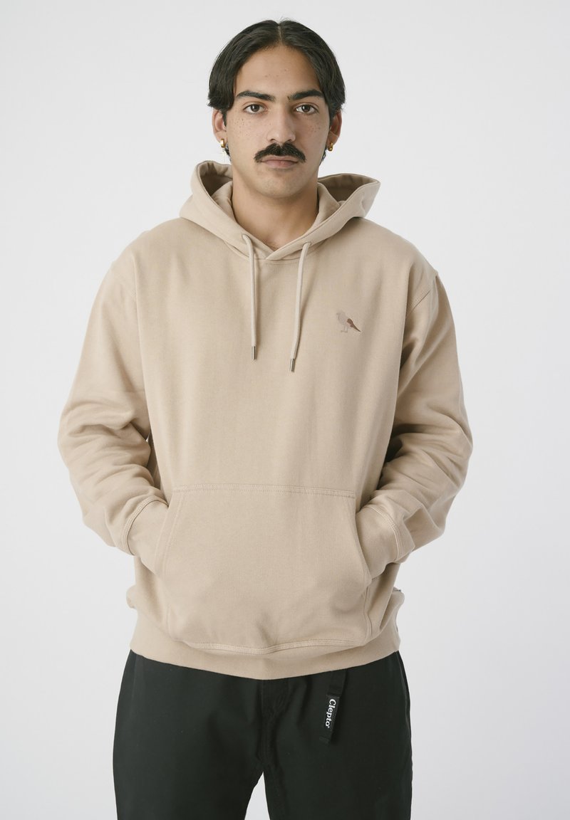 Beige Kapuzenpullover mit einer frontalen Kängurutasche, verstellbarem Kordelzug an der Kapuze und einem kleinen Vogel-Logo auf der Brust. Hergestellt aus weichem, strukturiertem Stoff.