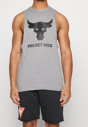 Muskelbepackte Person trägt ein ärmelloses graues Oberteil mit einem schwarzen Stier-Logo und dem Schriftzug "Project Rock", kombiniert mit schwarzen Shorts mit kleinem orangefarbenem Logo.