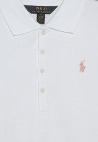 Bílá bavlněná polo košile Ralph Lauren s límečkem, čtyřmi knoflíky, velikost střední, a malým růžovým vyšitým logem na hrudi.