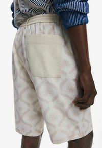 Şorturi bej deschise cu un model subtil, având o textură moale, cu un brâu elastic și o singură buză la spate, decorat cu un design delicat de curbe și stele.