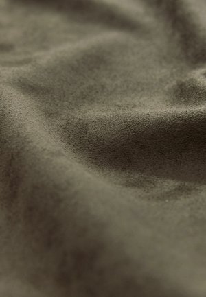 Tissu en daim vert olive avec une surface douce et texturée, présentant des ondulations et des plis, mettant en valeur son apparence lisse et mate.