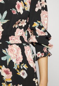 Vestido floral preto com um vibrante padrão de flores em tons de rosa e amarelo. Cintura elástica e punhos de mangas com babados, com uma textura suave.