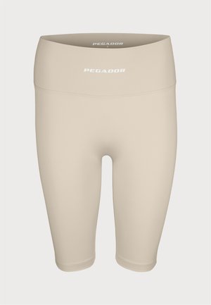 Beige stretch bike shorts with a high waistband, featuring a smooth texture and "PEGADOR" logo in white on the front.
