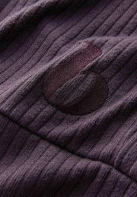 Purple textured fabric with vertical ribbing, featuring a dark circular logo. The material appears soft and slightly stretchable.