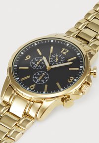 Gold metal wristwatch with a black dial, featuring silver hour markers, three sub-dials, and a link bracelet strap.