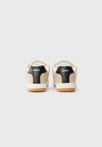 Beige sneakers med svarte hælaksenter og hvite gummisåler. Har en jevn tekstur og "ONLY"-logo bak.