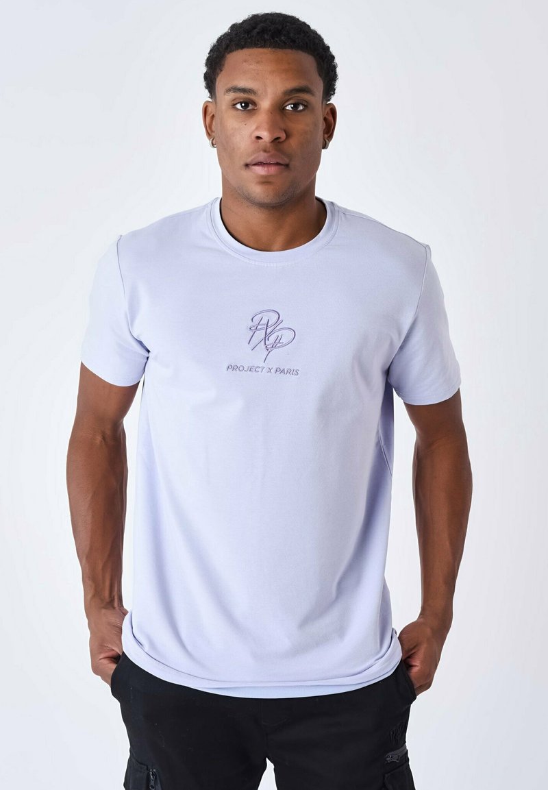 Camiseta de manga corta en lavanda claro con cuello redondo, que presenta un logotipo bordado en contraste con el texto "PROJECT X PARIS" en el pecho.