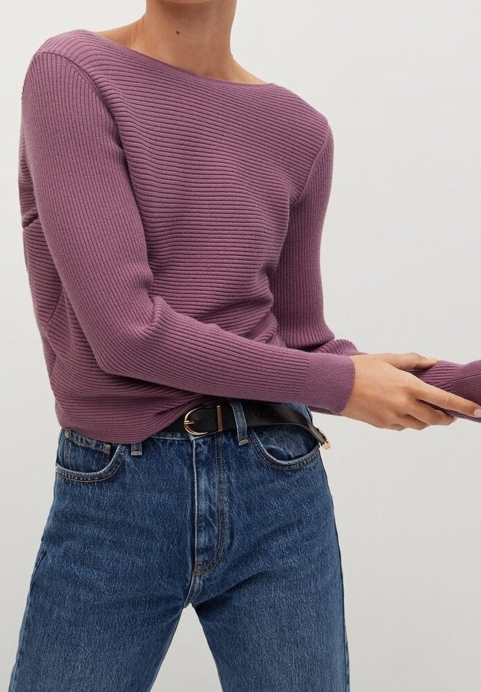 Maglione a coste di colore viola tenue con scollo ampio e maniche aderenti, abbinato a jeans di denim blu a vita alta e una cintura nera.